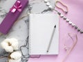 Set of women`s accessories desk - notebook with pen, gifts, jewelry, bracelet, cotton flowers on pink marble background. Workspac Royalty Free Stock Photo