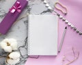 Set of women`s accessories desk - notebook with pen, gifts, jewelry, bracelet, cotton flowers on pink marble background. Workspac Royalty Free Stock Photo