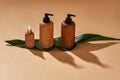 Set of wooden bottles or containers of different sizes on green leaf isolated on beige background. Zero waste and eco