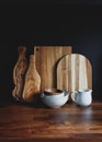 Set of wooden cutting board and ceramic dishes on a wooden kitchen table over black background. The concept of modern style rustic Royalty Free Stock Photo