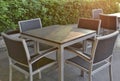 A set of wooden-steel table and rattan chairs on a roof deck floor beside a pool