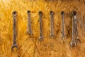 A set of wrenches hang on a wooden wall.