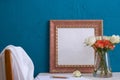 Set for writing, a bouquet of roses in a vase the back of a chair and a brown photo frame on a blue background Royalty Free Stock Photo