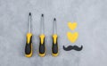 Set of yellow screwdrivers on a gray background.