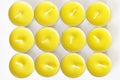 Set of yellow unlit new tea candles, top view.