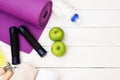 Set of Yoga practice with purple mat, dumbbell, towel, bottle of water and green apple, jump rope. Exercise equipment. Top view