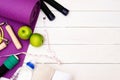 Set of Yoga practice with purple mat, dumbbell, towel, bottle of water and green apple, jump rope. Exercise equipment. Top view