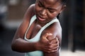 Setbacks are temporary. a young woman holding her shoulder in pain while at the gym.