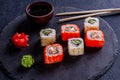 Seth sushi roll with salmon, eel, tuna, avocado, cucumber, Philadelphia cheese, tobik caviar, on a black slate board, dark Royalty Free Stock Photo