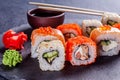 Seth sushi roll with salmon, eel, tuna, avocado, cucumber, Philadelphia cream cheese, tobik caviar, on a black slate board, dark Royalty Free Stock Photo