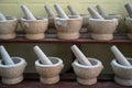 Sets of mortar and pestle in light grey color granite stone arranging on wooden shelf for sale in local market