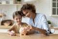 Friendly mom and daughter kid thrift coins in piggybank