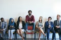 Setting himself apart from the crowd. Portrait of a happy job applicant sitting in a row with a group of well-dressed