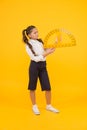 Setting square with protractor. Little girl using triangle to measure angles in degrees on yellow background. Small