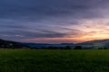 Setting sun in the Beskydy Mountains colored sky orange and blue, dark color clouds and fresh mist which formed under the mountain Royalty Free Stock Photo