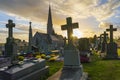 The setting sun disappears behind a funerary monument in the old cemetery next to the church of Montpinchon in Normandie, France