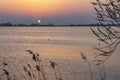 The setting sun almost disappears behind the shore of Lake Zoetermeerse Plas in Zoetermeer, The Netherlands