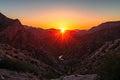 setting sun, fiery canyon and silhouette of mountain range in the background