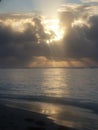 The setting sun, hidden in the cloud, reflects in the sea Royalty Free Stock Photo