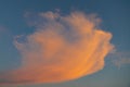 Orange cloud blowing over evening sky, sun set illuminates sweeping cloud