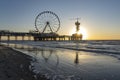 The setting sun is just behind the Pier in Scheveningen with the ferris wheel and the bungy jump tower Royalty Free Stock Photo
