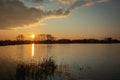 Setting sun and large cloud over a calm lake, evening view Royalty Free Stock Photo