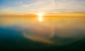 Setting sun over calm water with cloud reflections.