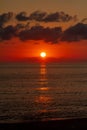 The setting sun over the surface of the sea, illuminating the sky in blood-red color Royalty Free Stock Photo