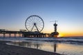 The setting sun shines through the rear pillars of the Pier in Scheveningen with the ferris wheel and the bungy jump tower Royalty Free Stock Photo