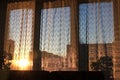 The setting sun shines through the tulle on the window. Contour evening light. Royalty Free Stock Photo