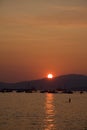 Setting sun silhouettes people and boats, English Bay,