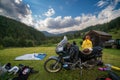 Setting up a blue tent with a great view of the mountains. A trip on a motorbike. A touring motorcycle with lots of gear. Bags,