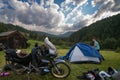 Setting up a blue tent with a great view of the mountains. A trip on a motorbike. A touring motorcycle with lots of gear. Bags,