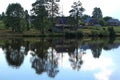 A settlement is located with one-story buildings, located on the shore of the reservoir, in the middle of summer.