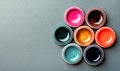 Seven beautiful, bright, mother-of-pearl, multicolored open cans of paint on a bright colored background.