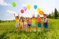 Seven children with balloons in green field Royalty Free Stock Photo