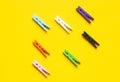 Seven colored clothespins in a row on a yellow background