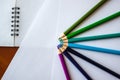 Seven colored pencils lie in a semicircle on white sheets of paper Royalty Free Stock Photo