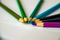Seven colored pencils lie in a semicircle on white sheets of paper Royalty Free Stock Photo
