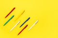 Seven colorful ballpoint pens on a bright yellow background. Top view, copy space for text
