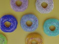 Seven colorful donuts on a yellow background