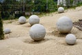 Seven concrete round spheres on sand in a garden