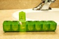 Seven day green pill box with pills sits on countertop Royalty Free Stock Photo