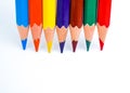 Seven different colored wood pencil crayons placed in line on a white background Royalty Free Stock Photo