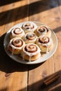 Seven frosted cinnamon rolls on white plate with cinnamon sticks Royalty Free Stock Photo