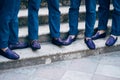 Seven groom& x27;s best men in identical blue trousers and shoes stand on the stairs, close-up