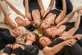 Seven happy women lie on their backs on the floor with their hea