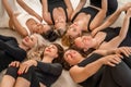 Seven happy women lie on their backs on the floor with their heads pressed together.