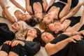 Seven happy women lie on their backs on the floor with their hea