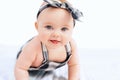 Cute smiling little baby girl sitting on bed. Seven month old infant child on grey soft blanket Royalty Free Stock Photo